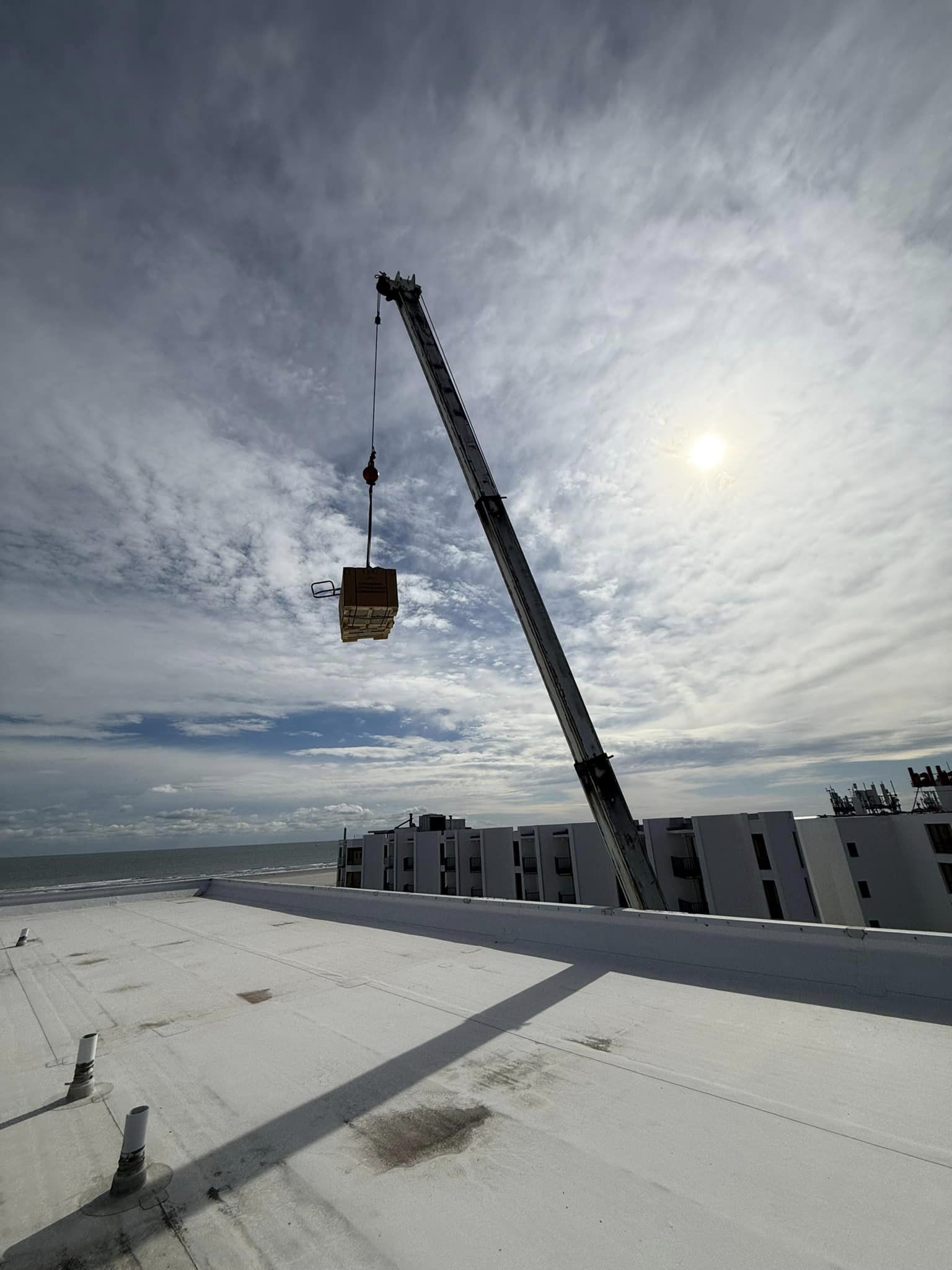 A Crane Hoists A Large Box Onto The Rooftop Of A Building